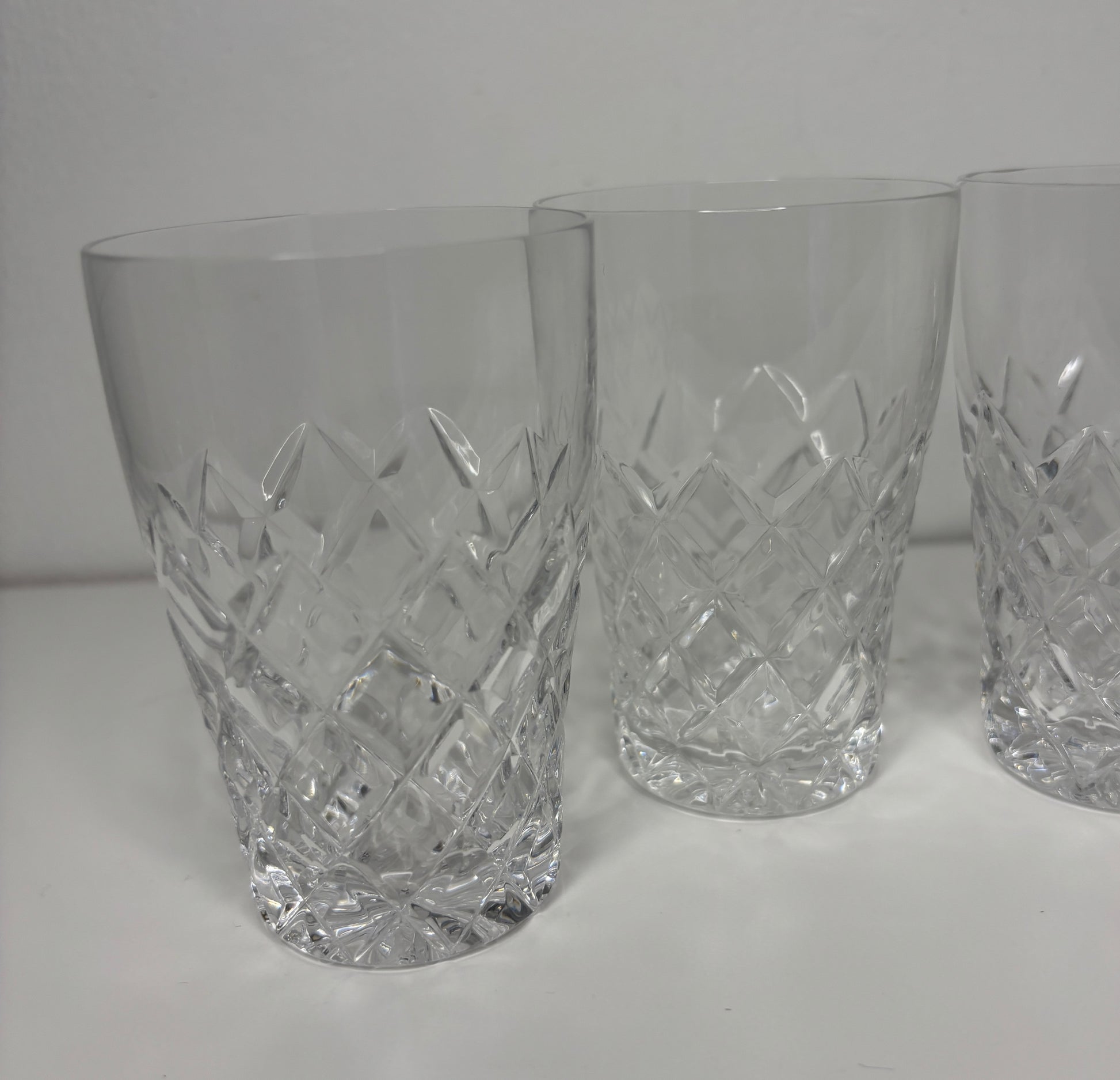 Three crystal glasses with diamond cut pattern on a white background