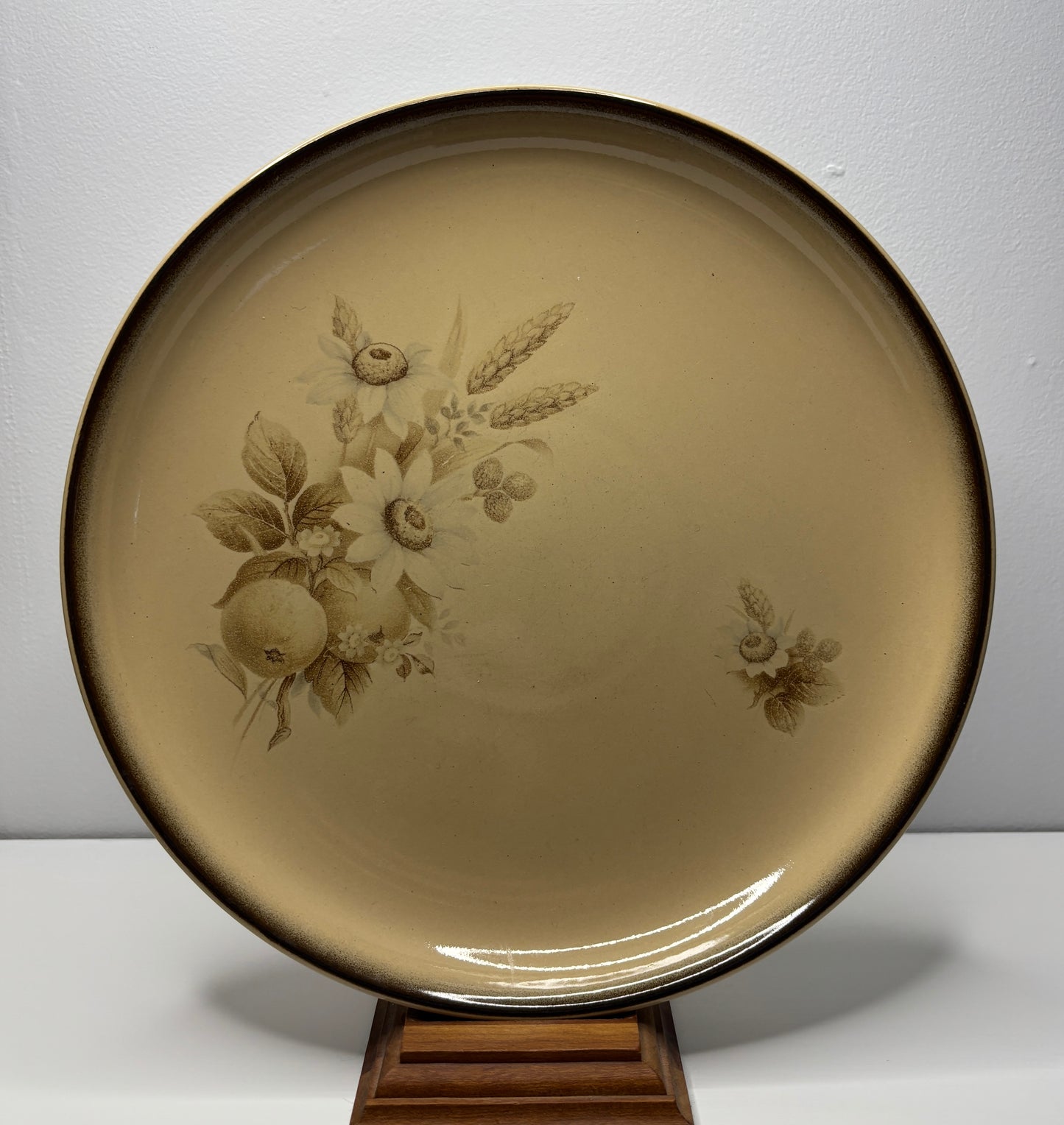 Beige ceramic plate with floral design on a stand against a gray background