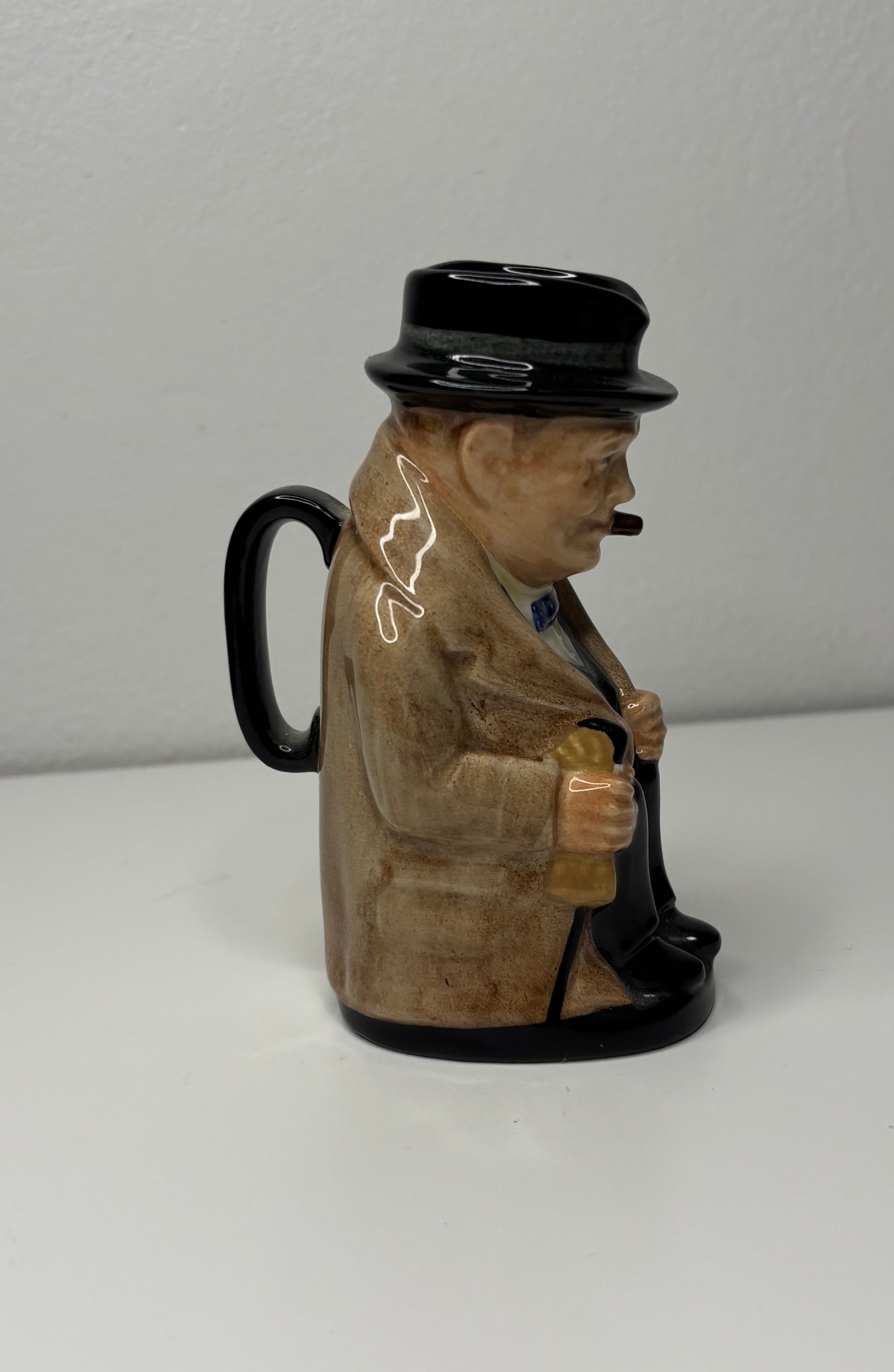 Figure of a man in a suit and top hat holding a cane on a white background
