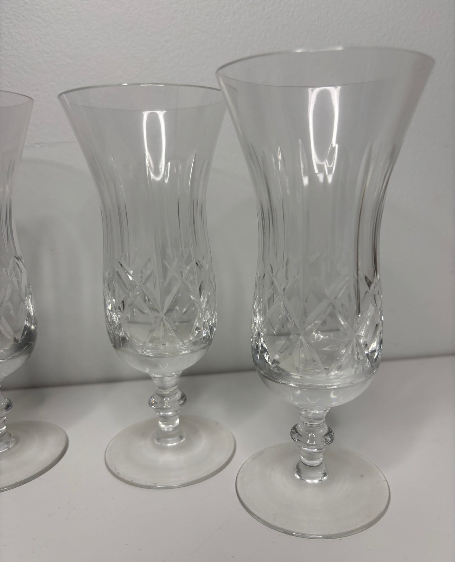 Set of three clear glass goblets with intricate designs on a white surface.