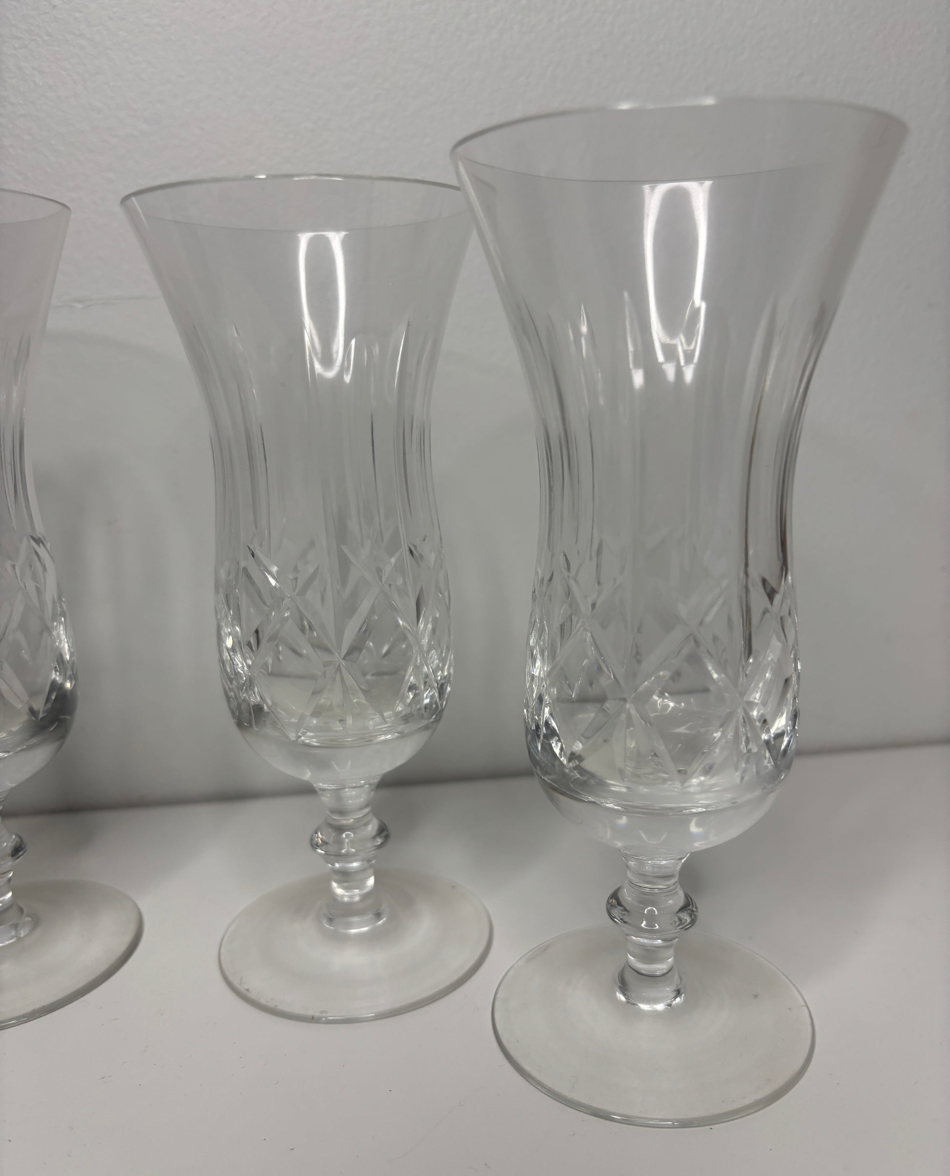 Set of three clear glass goblets with intricate designs on a white surface.