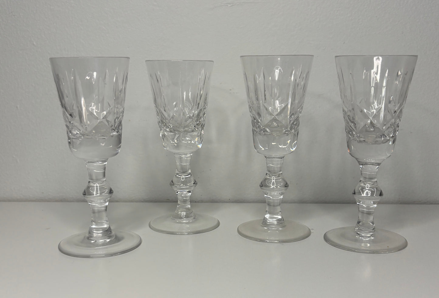 Four clear glass goblets on a white surface with a gray background