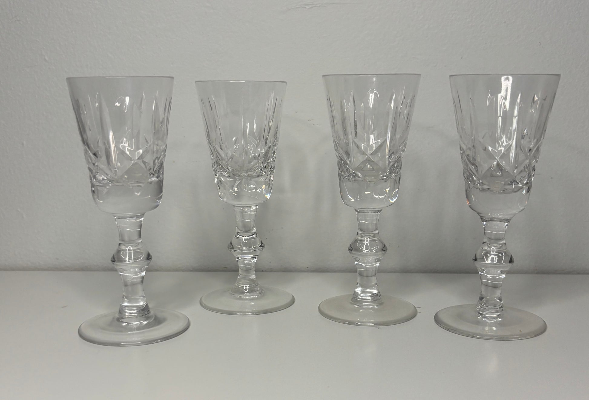 Four clear glass goblets on a white surface with a gray background