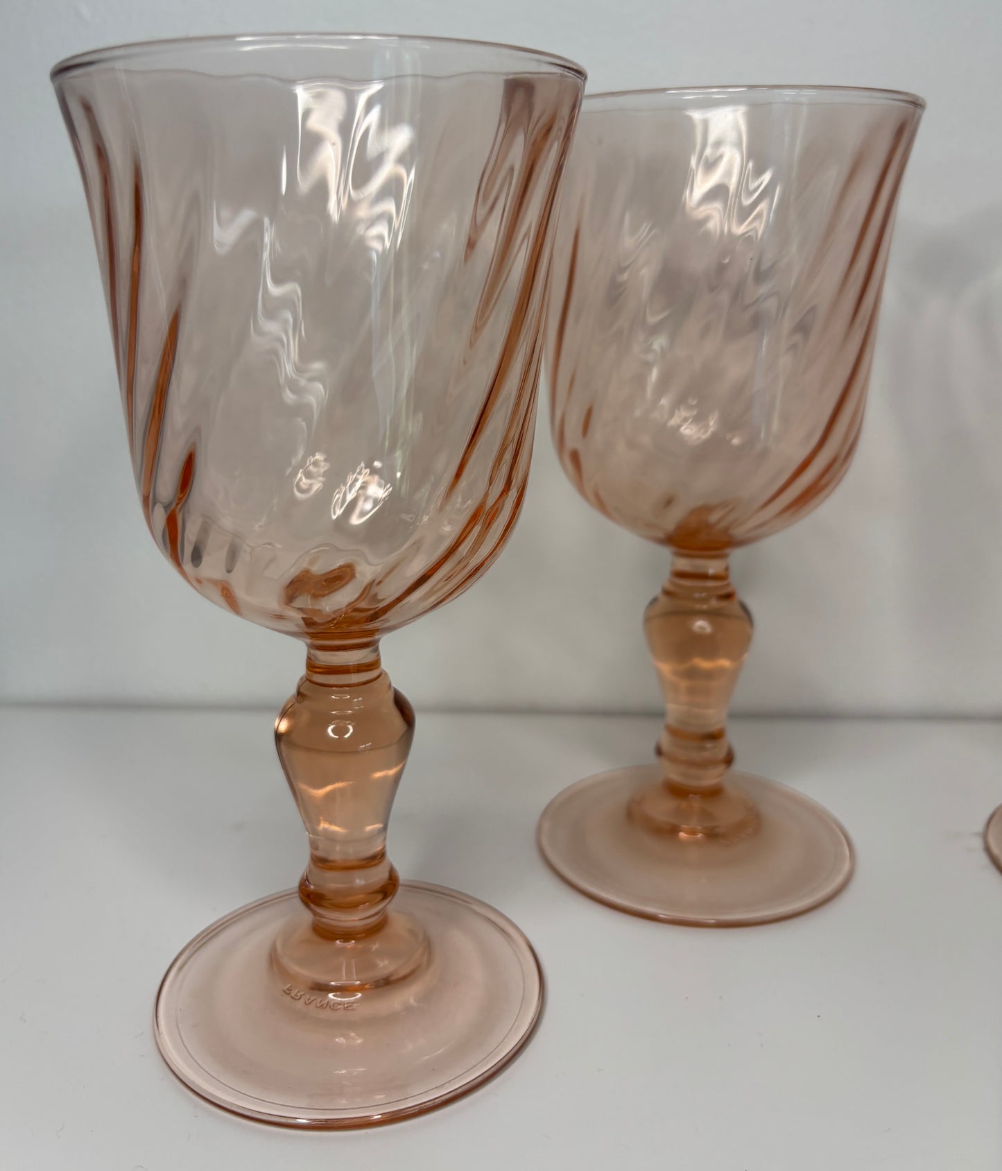 Two pink glass goblets on a white surface with a white background