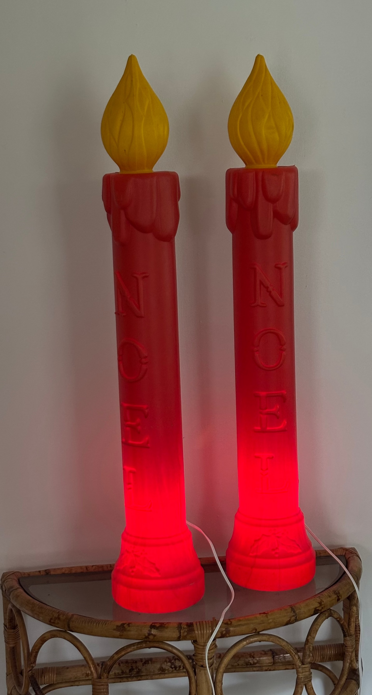 Two red candle-shaped lamps with yellow flames on a decorative stand.