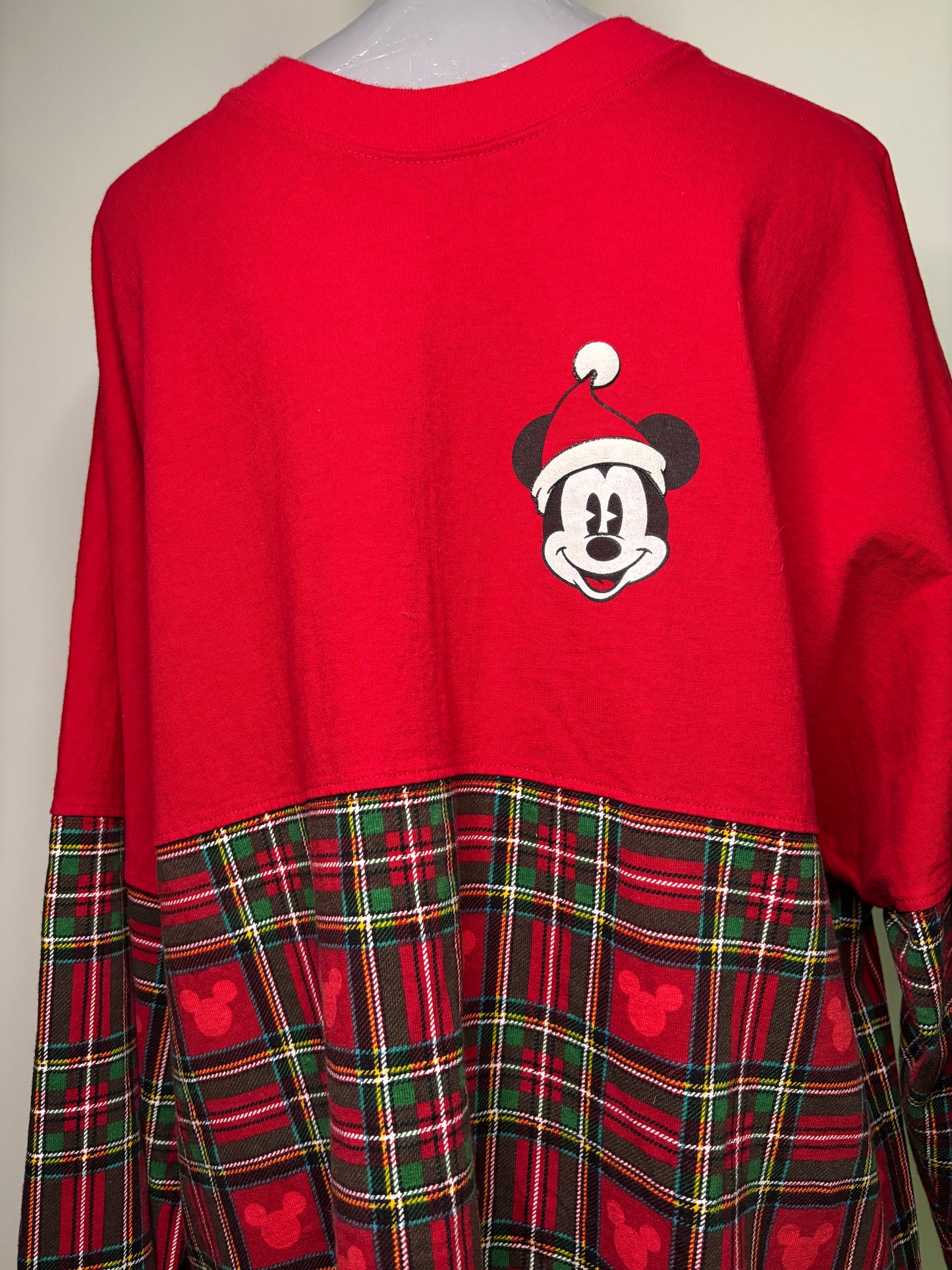 Red top with a mickey mouse character and plaid skirt on a mannequin against a neutral background