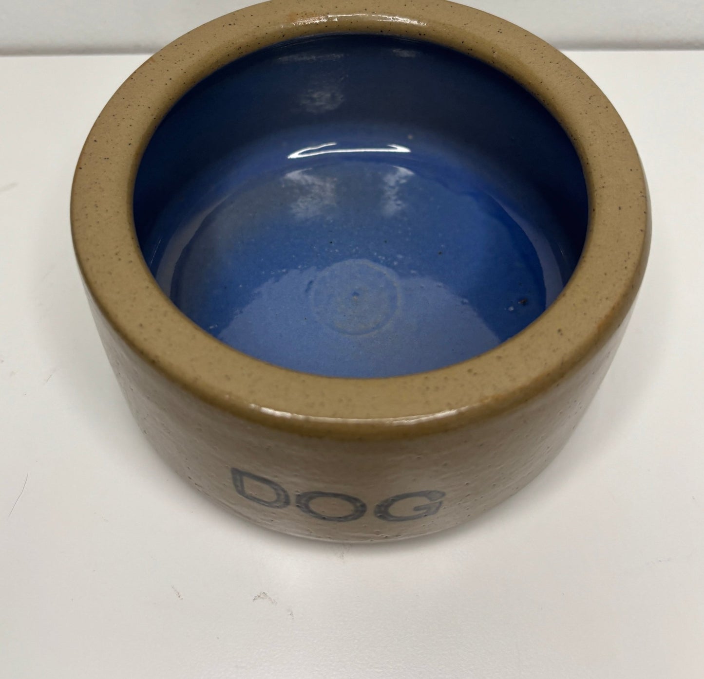 Ceramic dog bowl with blue interior and brown exterior on a white background
