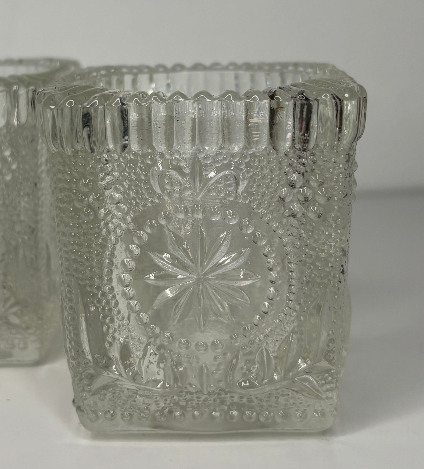Decorative glass candle holders with intricate patterns on a white background