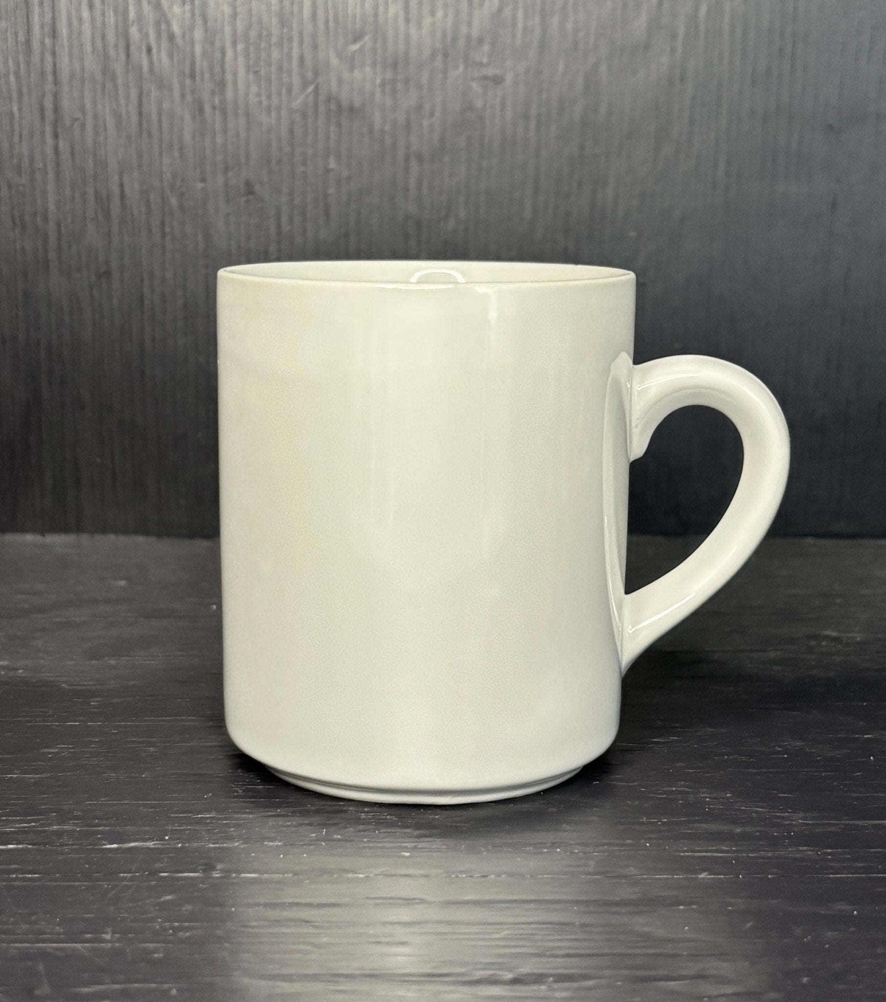 White ceramic mug on a dark wooden surface with a dark background