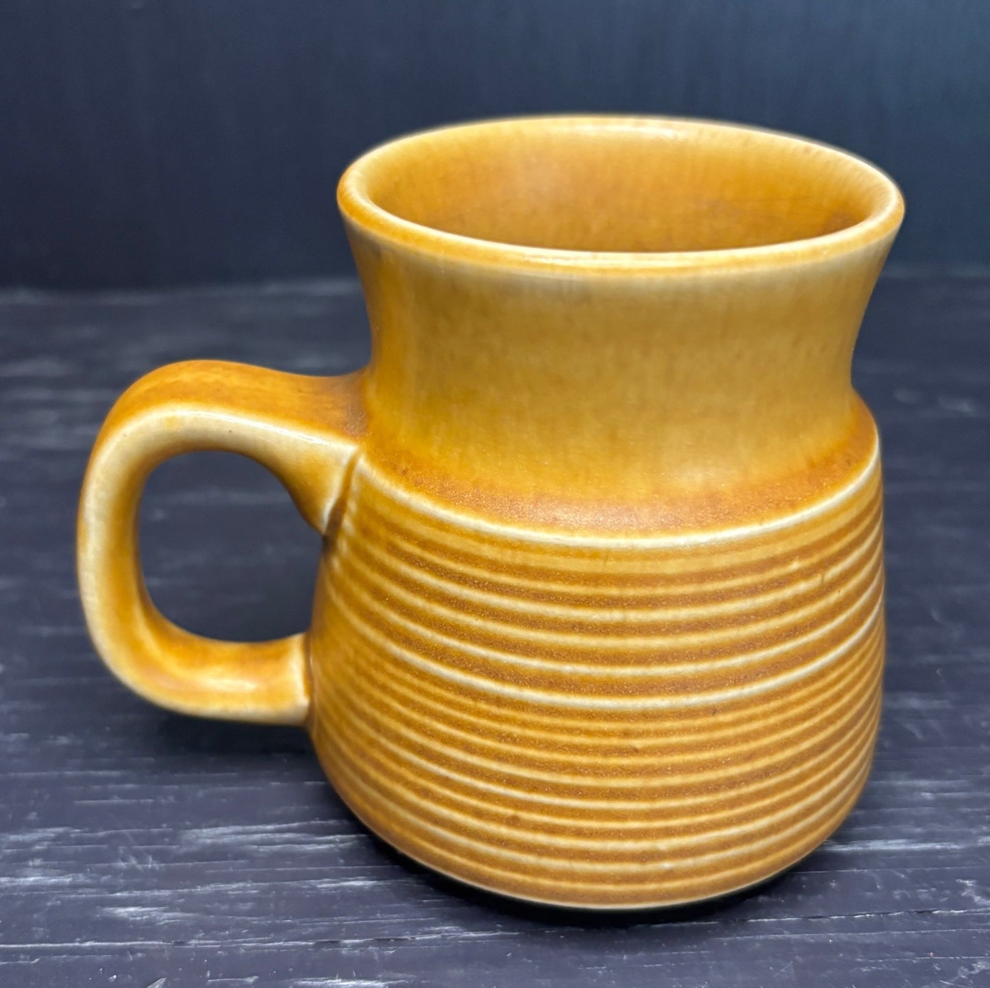 brown ceramic mug with ribbed texture on a dark background