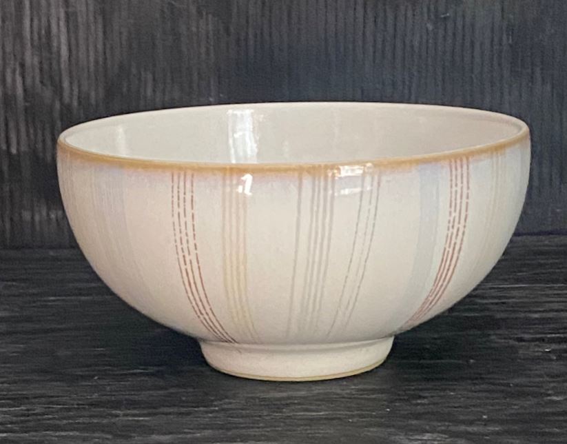 Ceramic bowl with beige interior and brown exterior on dark wooden surface