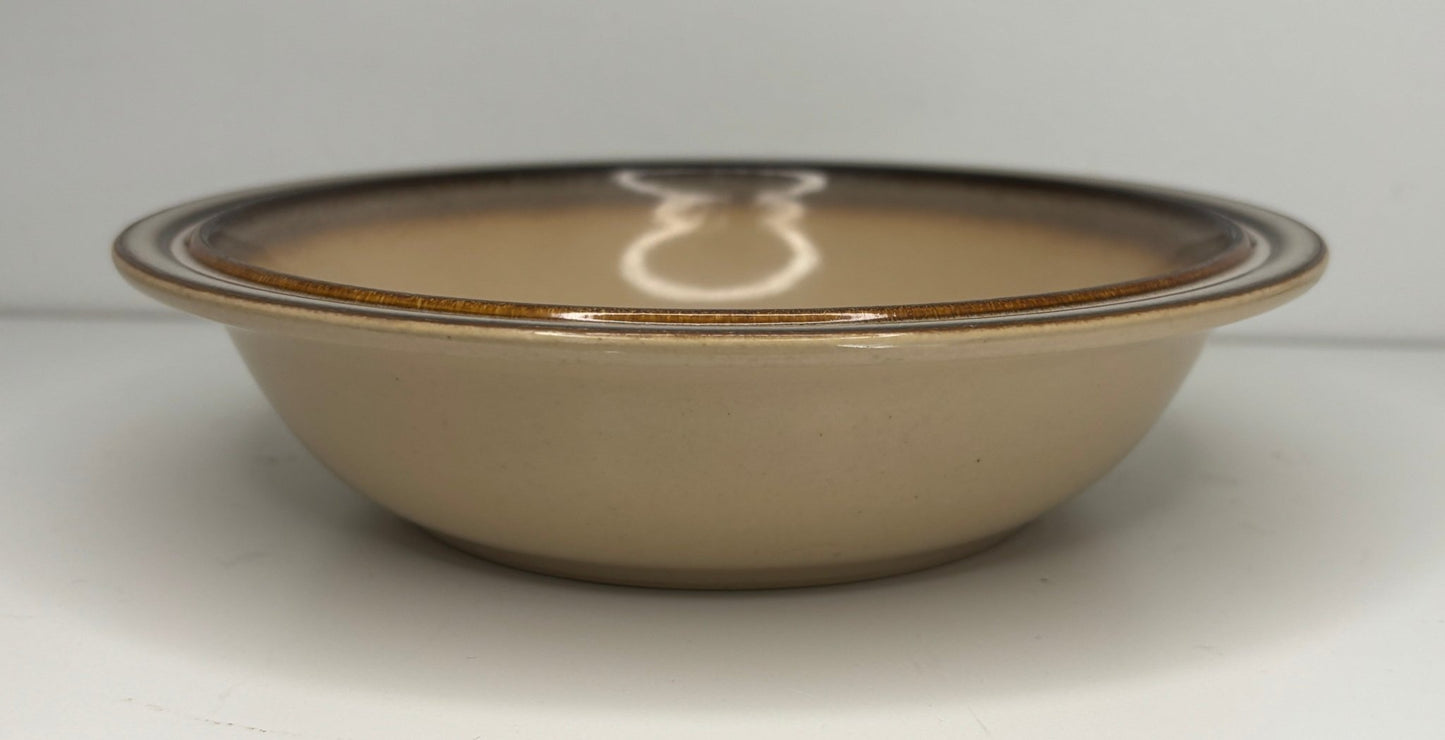 Beige ceramic bowl with brown rim on a white background