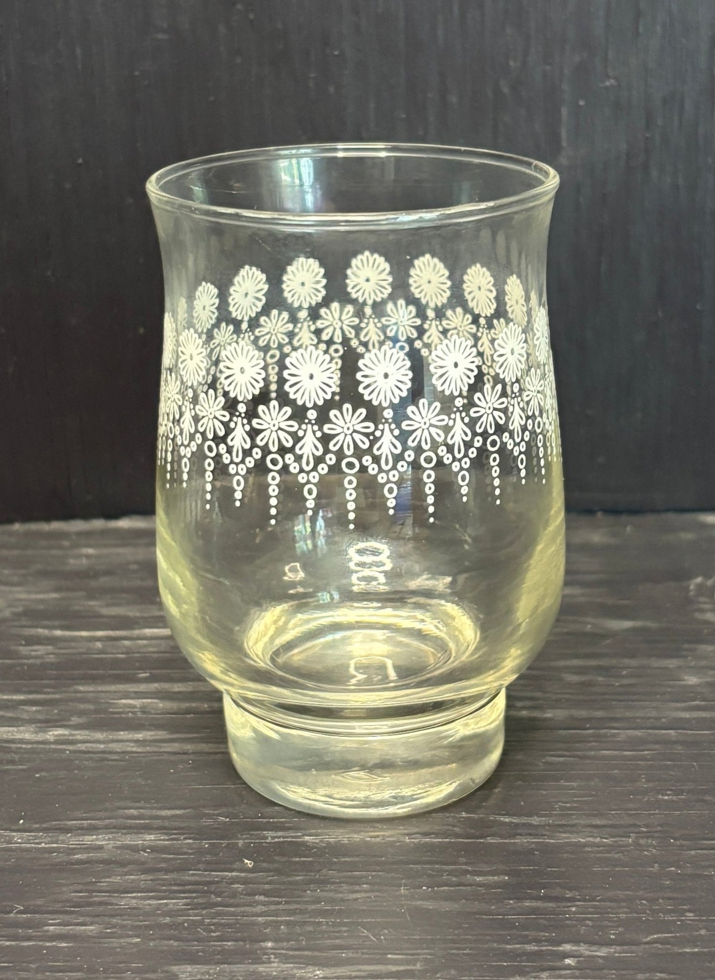 Clear glass with white floral pattern on a dark surface