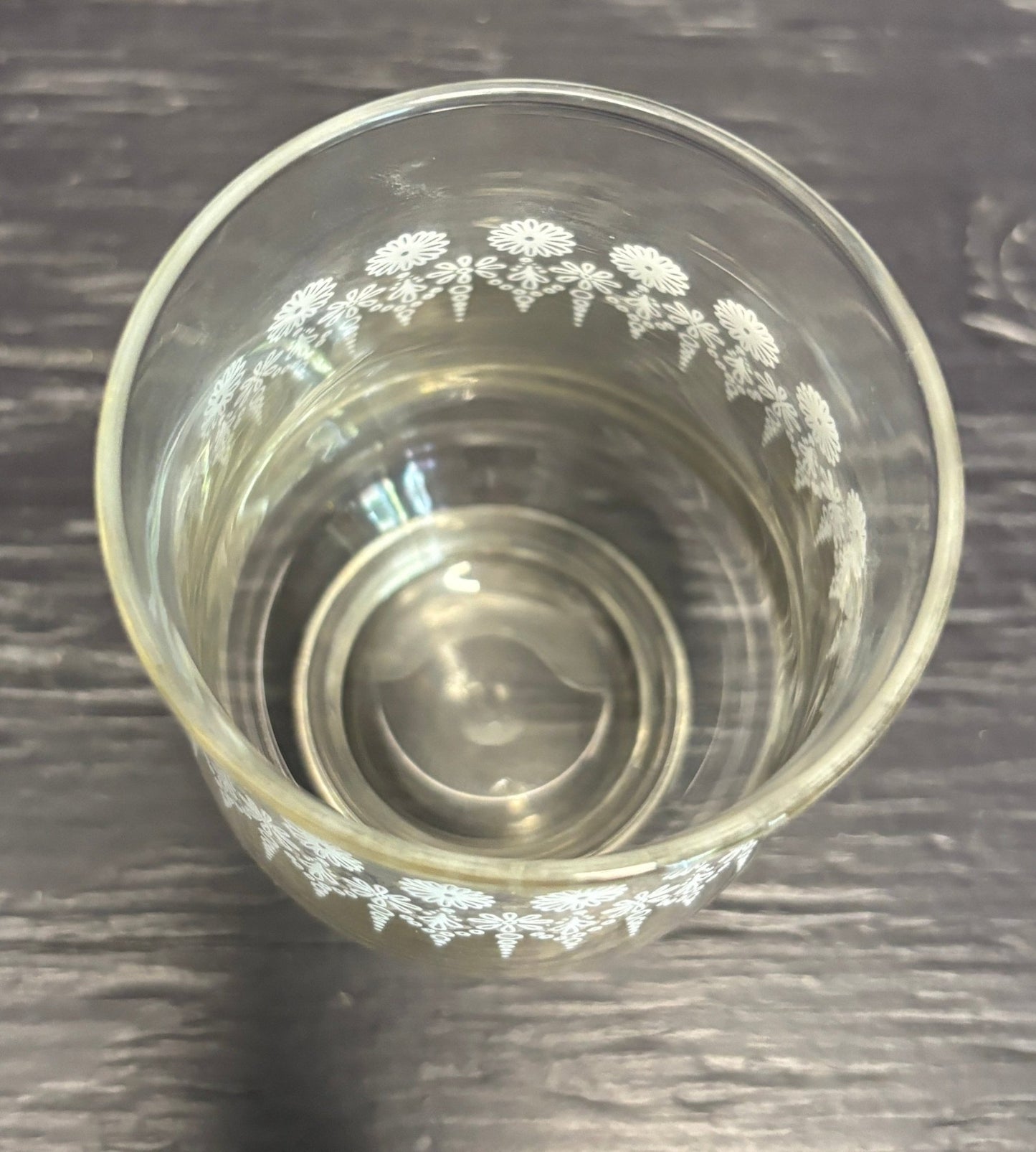 Clear glass with floral etching on a dark wooden surface