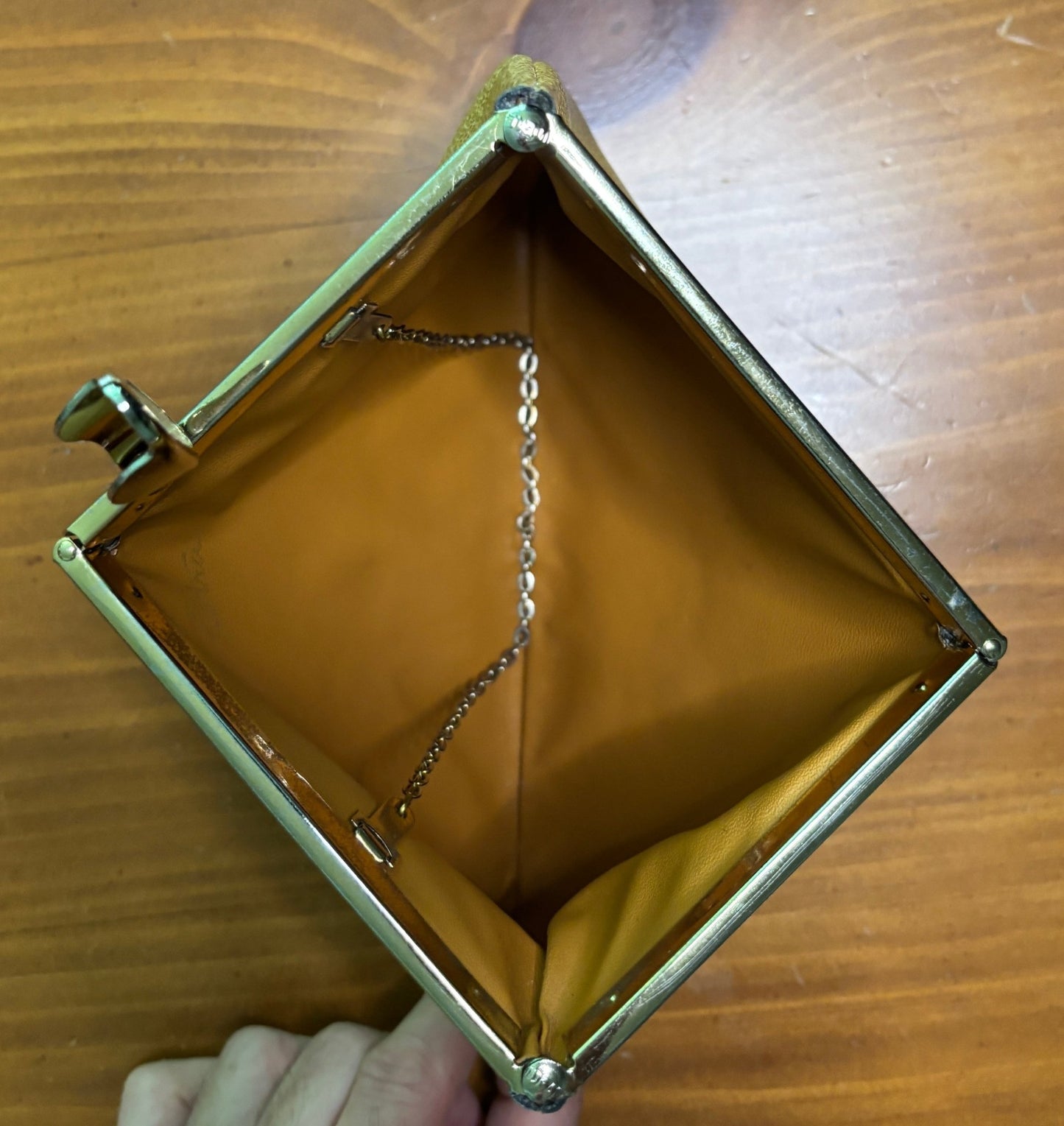 Empty gold clutch purse on a wooden surface