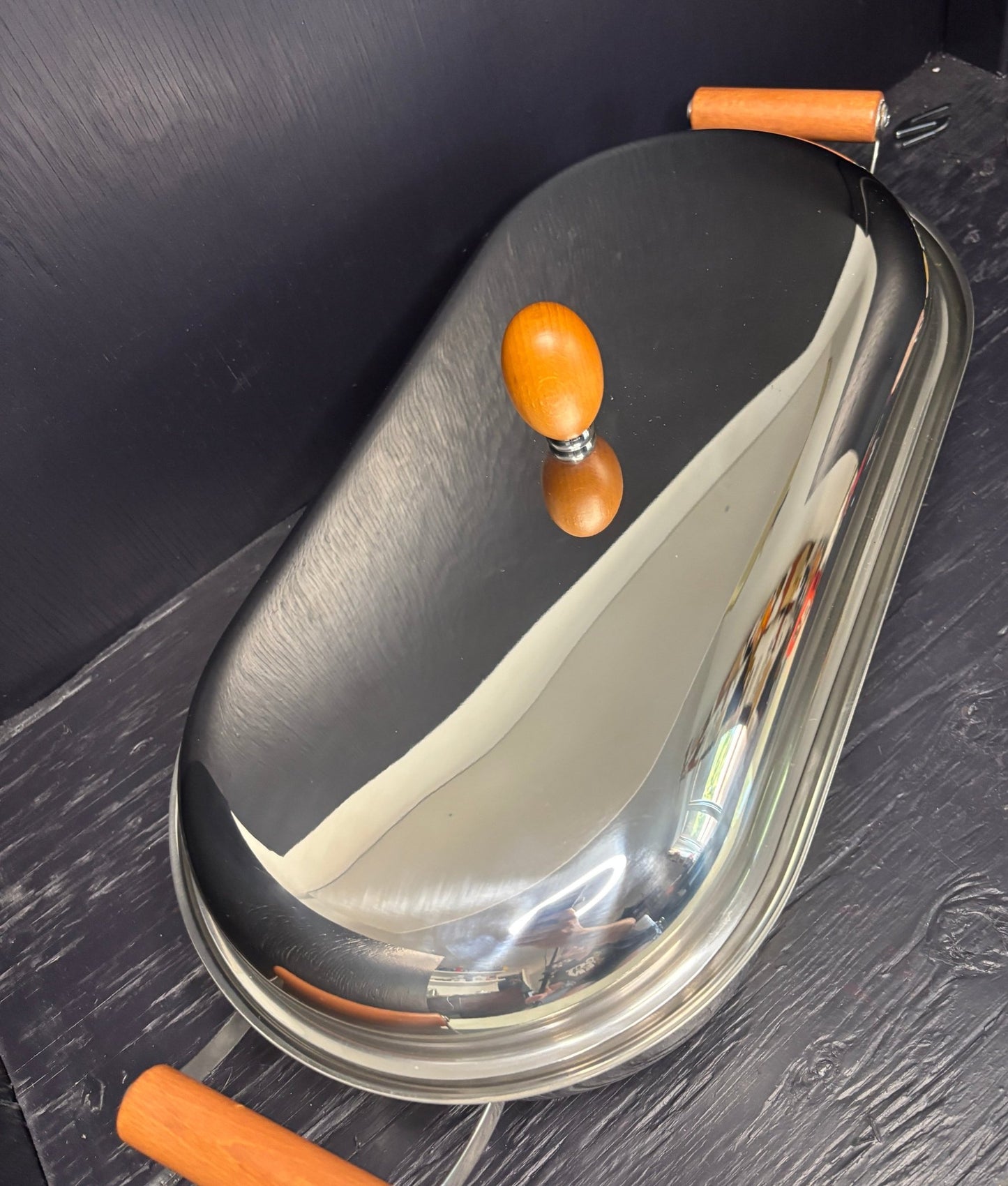 Metallic pan with wooden handle on a dark surface
