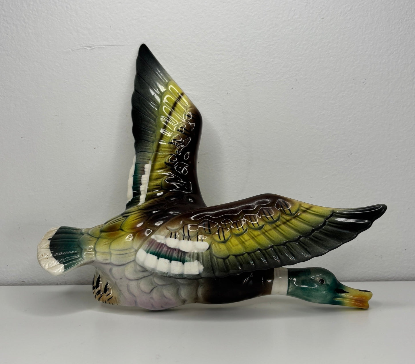 Decorative bird figurine with open wings on a white surface and light gray background