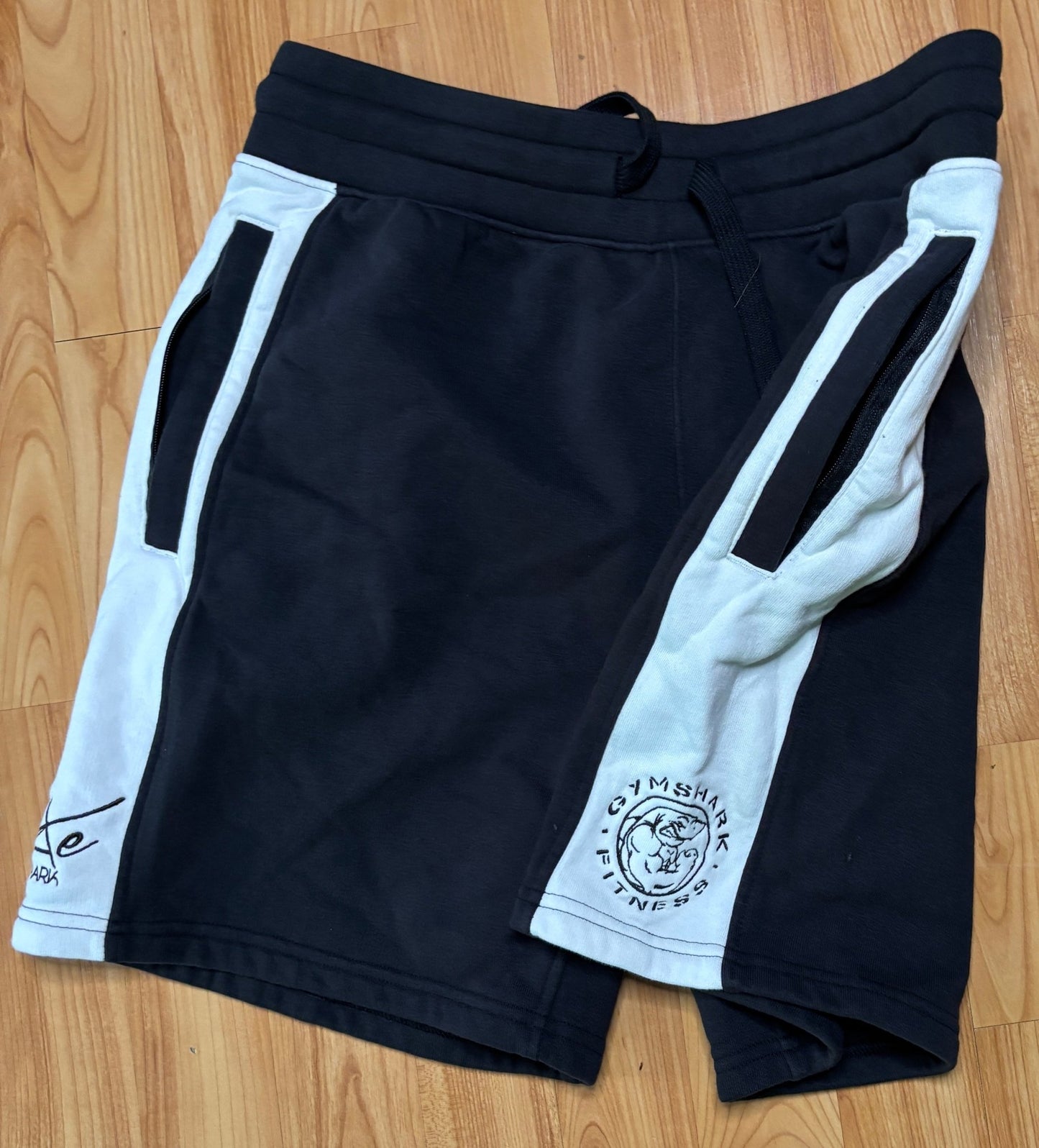 Black shorts with white accents on a wooden floor