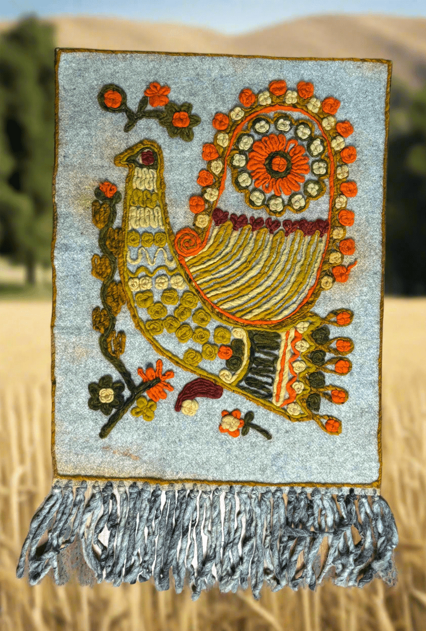 Decorative wall hanging with a bird design and floral elements against a natural background.