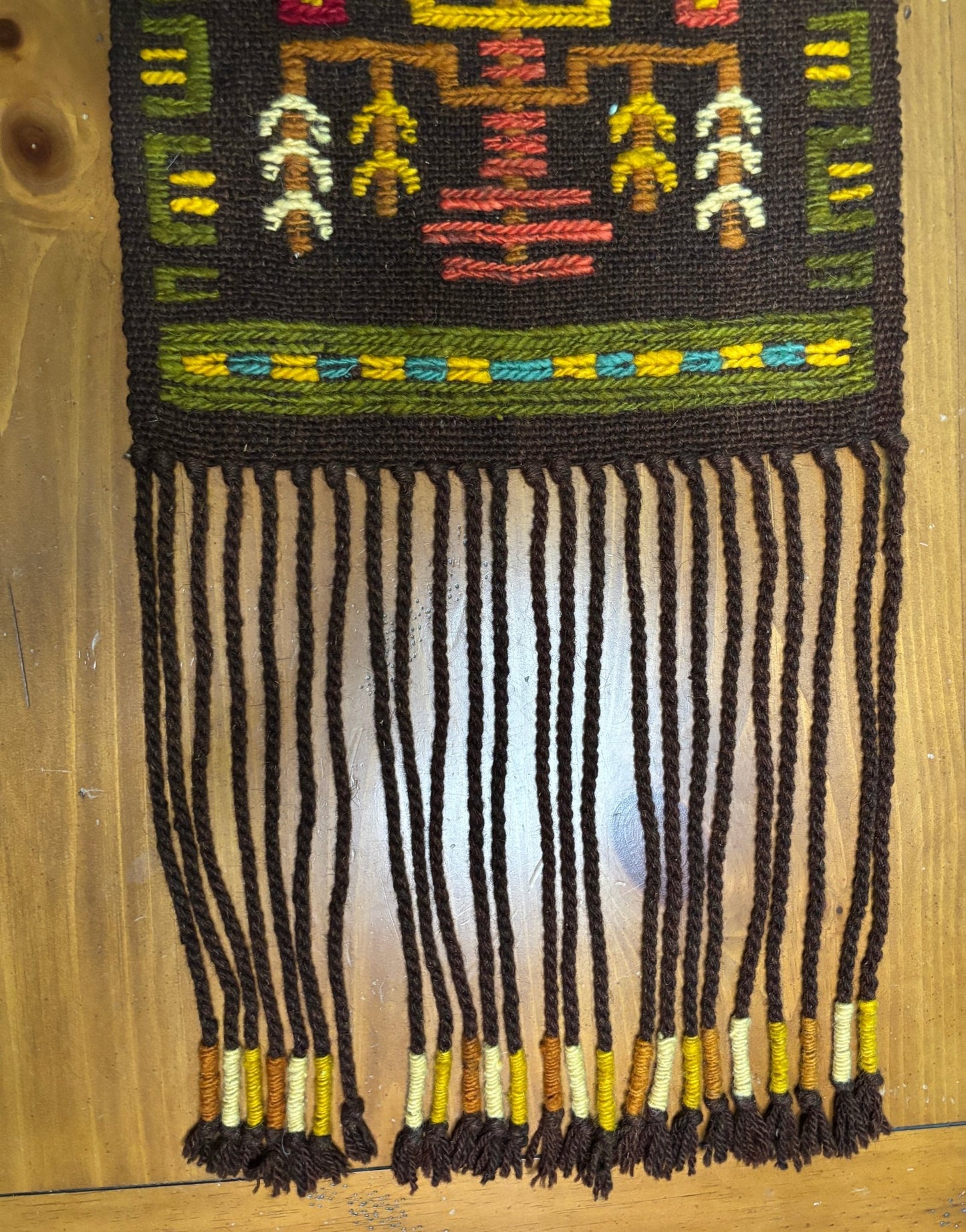 Textile with intricate patterns and fringes on a wooden surface