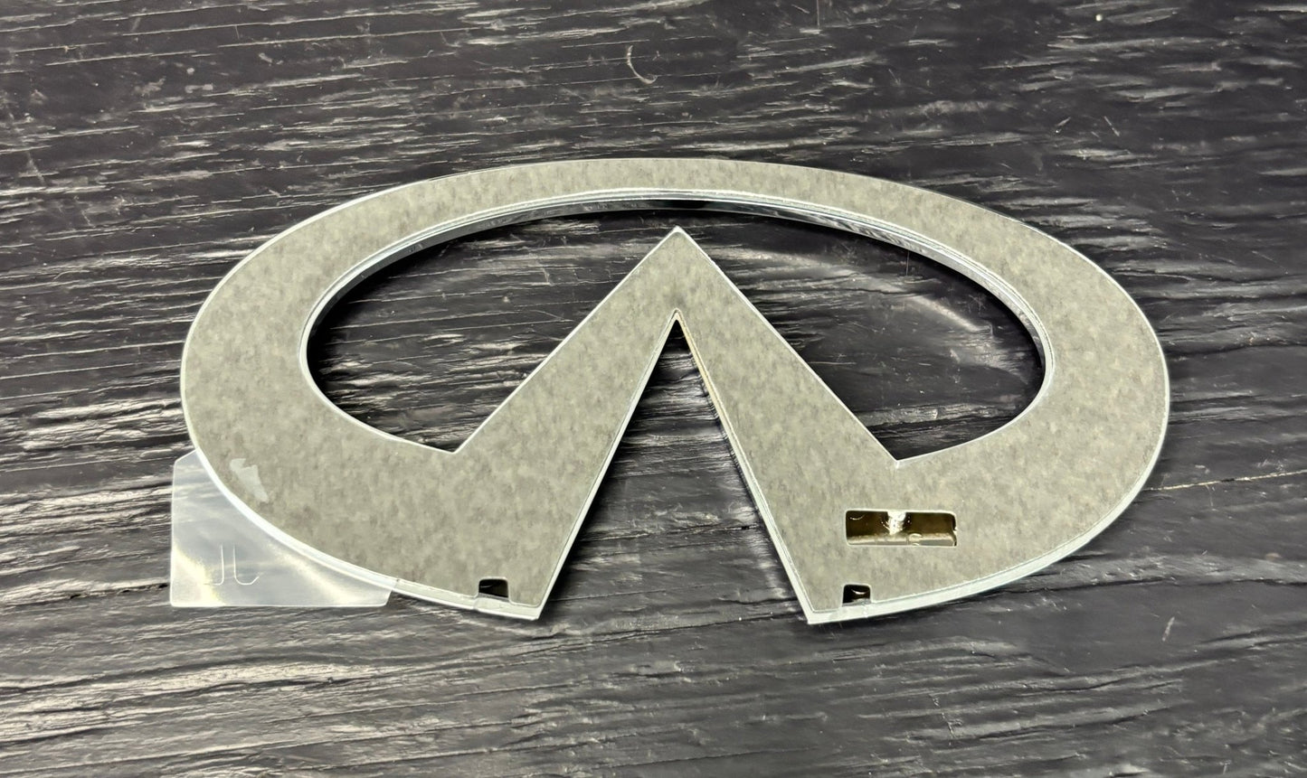 Metallic Infiniti logo on a wooden surface