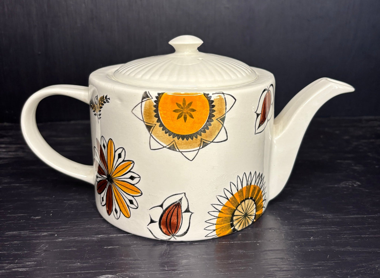 Ceramic teapot with floral patterns on a dark surface