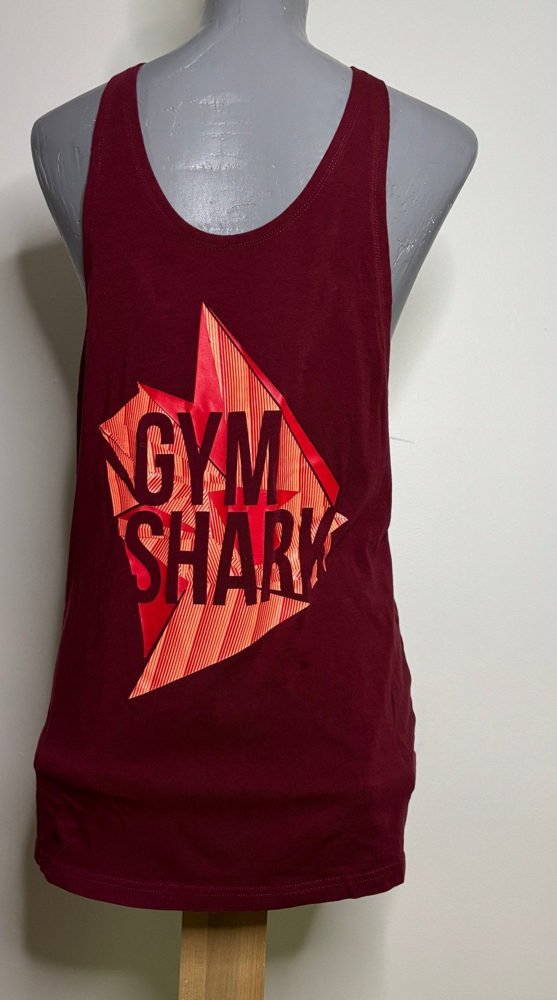 Maroon tank top with 'Gym Shark' logo on a mannequin against a white wall.