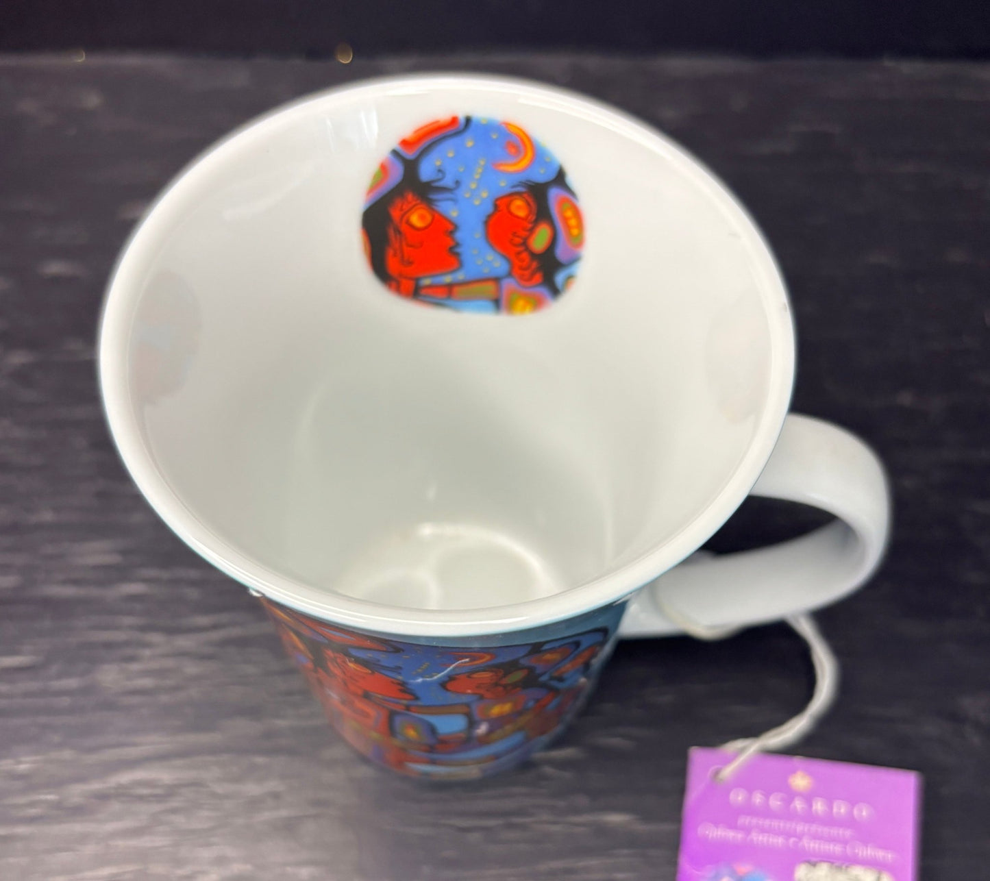 White mug with colorful design on a dark surface