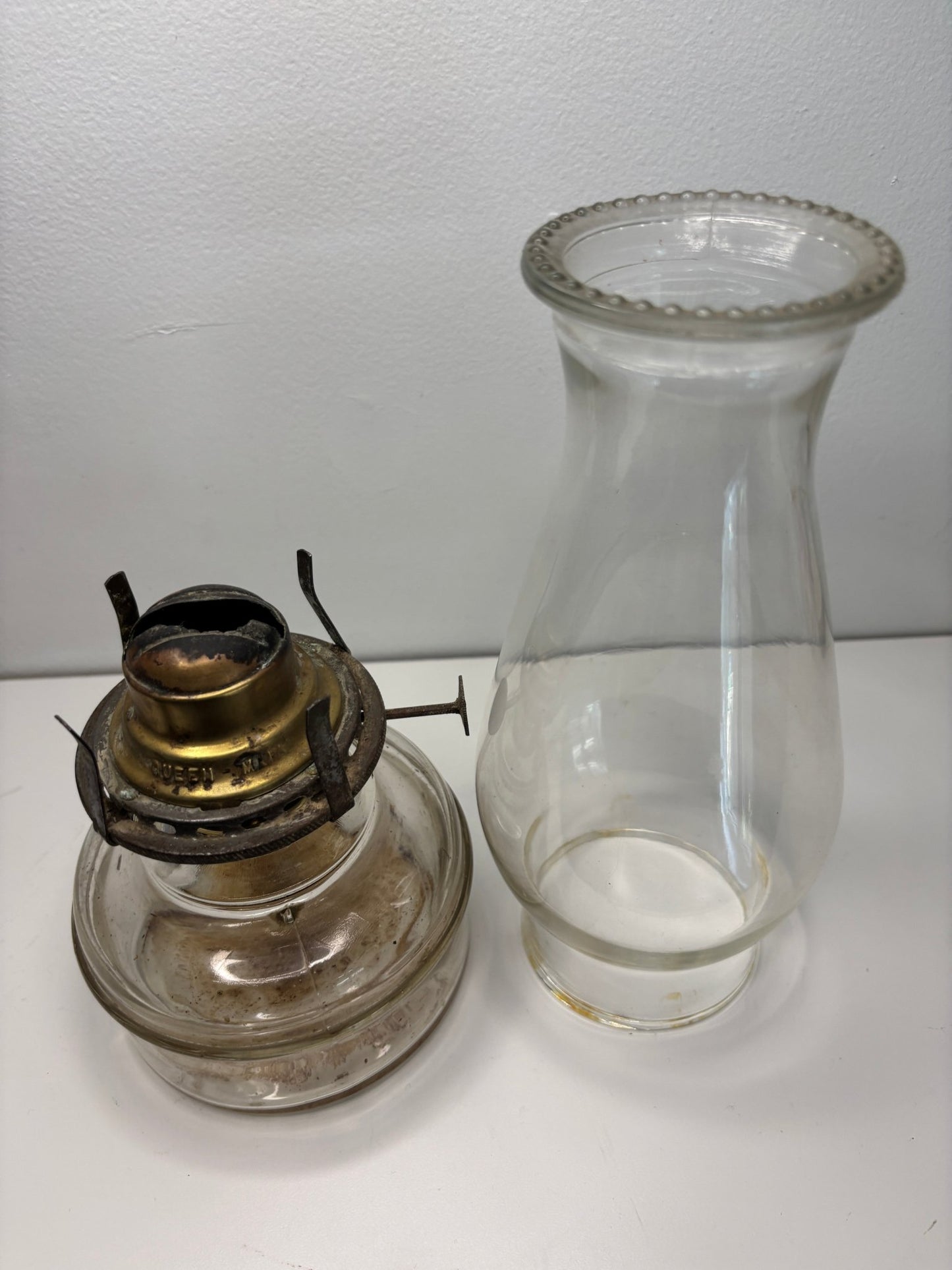 Vintage oil lamp with clear glass reservoir and brass base on a white background