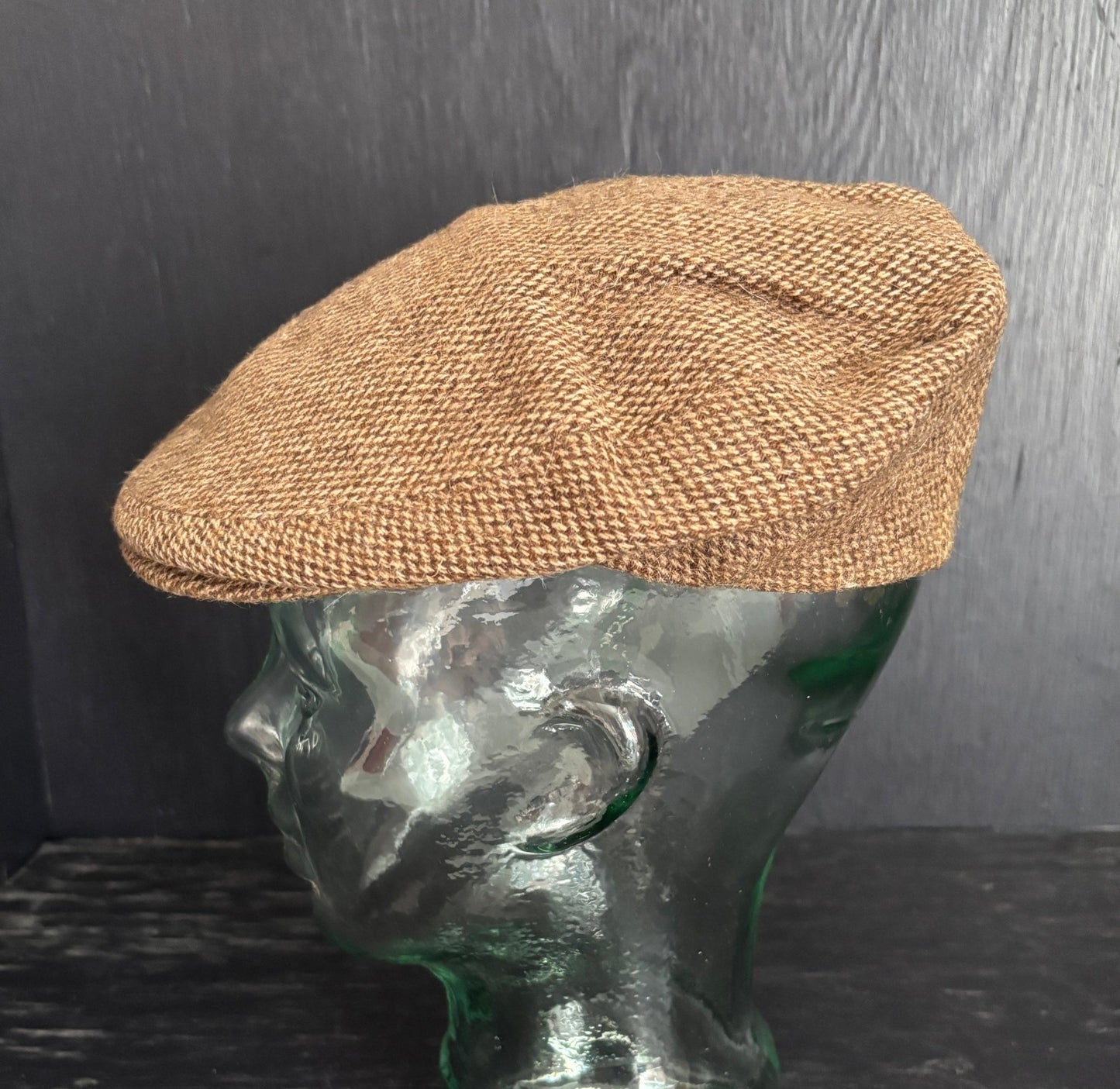 Brown textured flat cap on a mannequin head against a dark background