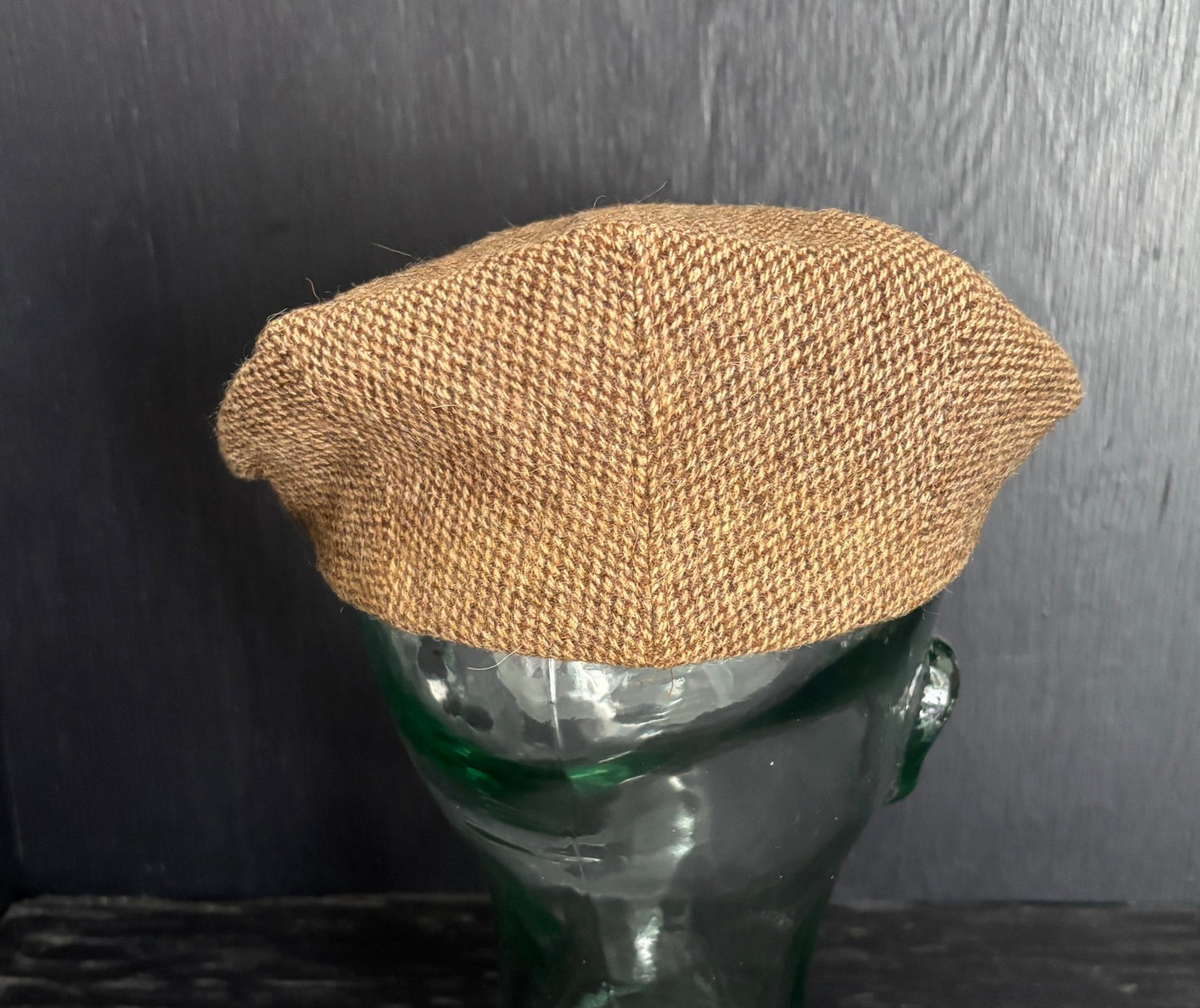 Brown woven beret on a mannequin head against a dark background