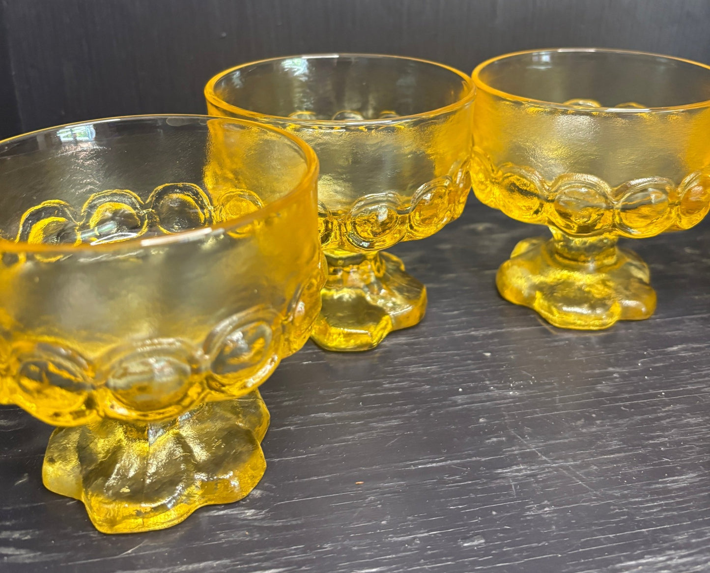 Three yellow glass goblets with footed bases