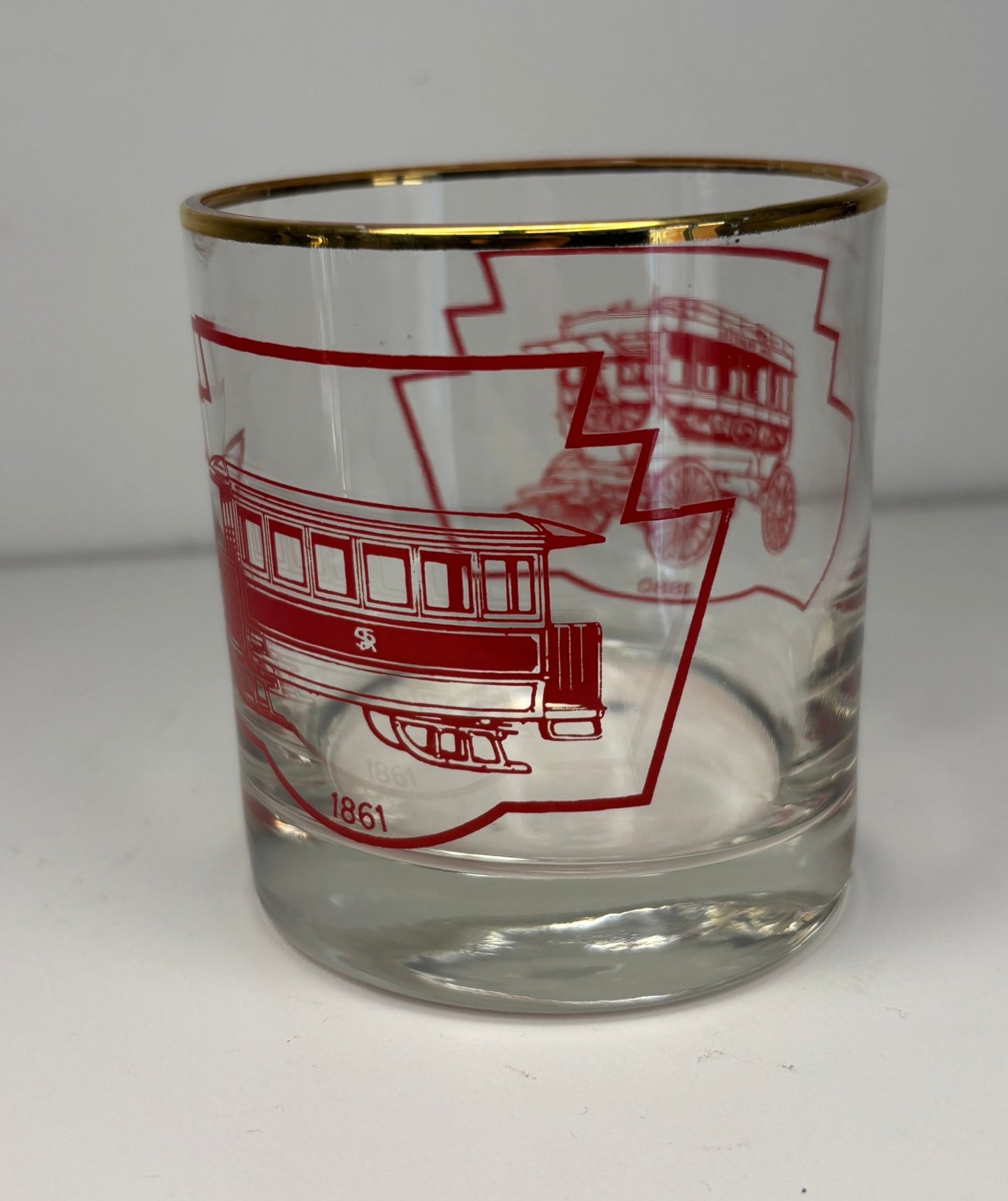 Clear glass with red trolley design and gold rim on a white background