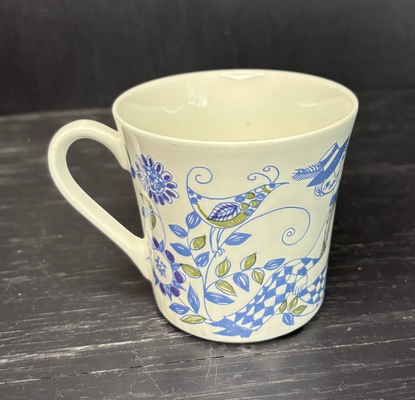 White mug with blue floral and bird pattern on a dark surface