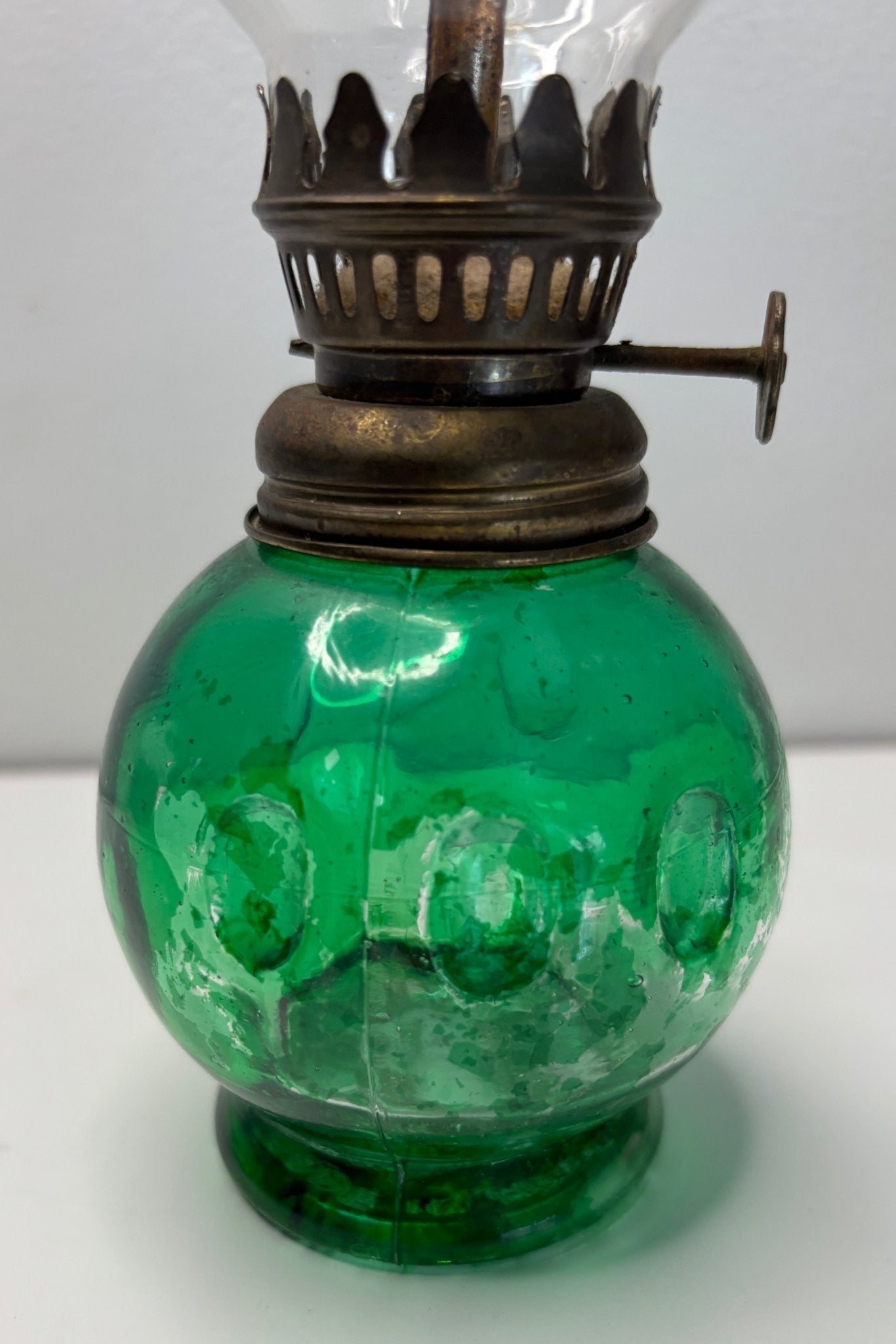 Green glass oil lamp with brass fitting on a white background