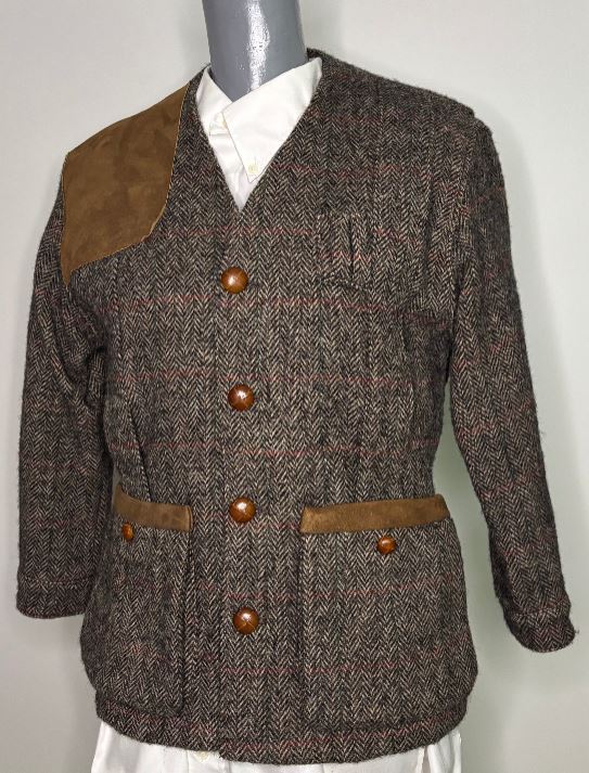 Herringbone jacket with brown leather accents on a mannequin against a white background