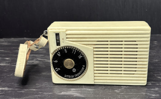 Vintage beige radio with a black dial on a dark surface