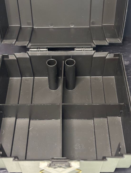 Black metal tool box with open lid showing two cylindrical components inside.