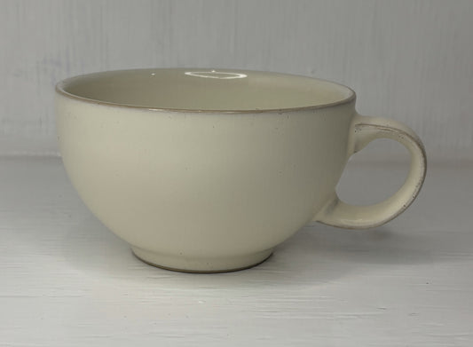 Beige ceramic mug on a light wooden surface