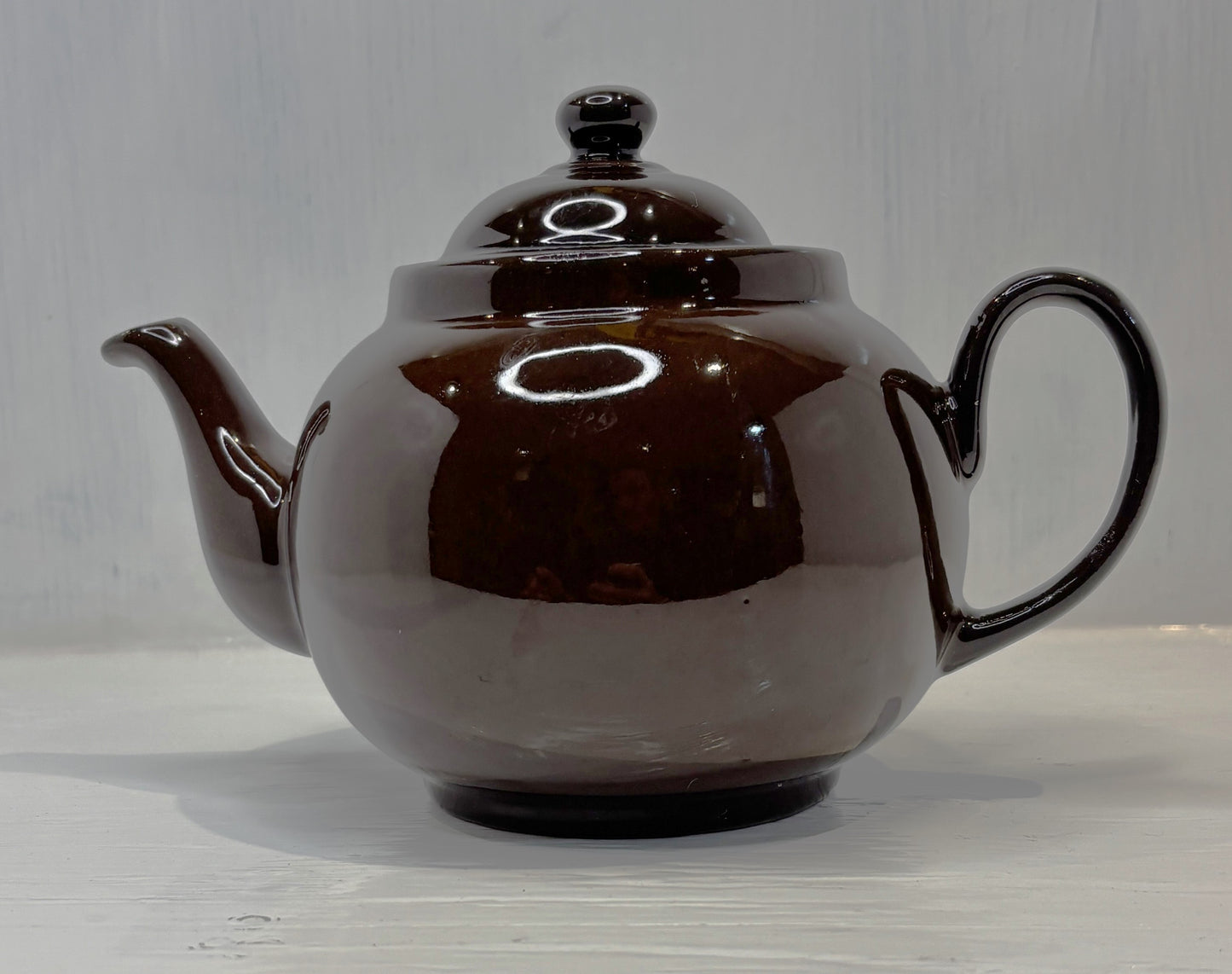 Brown teapot with a lid on a light wooden surface