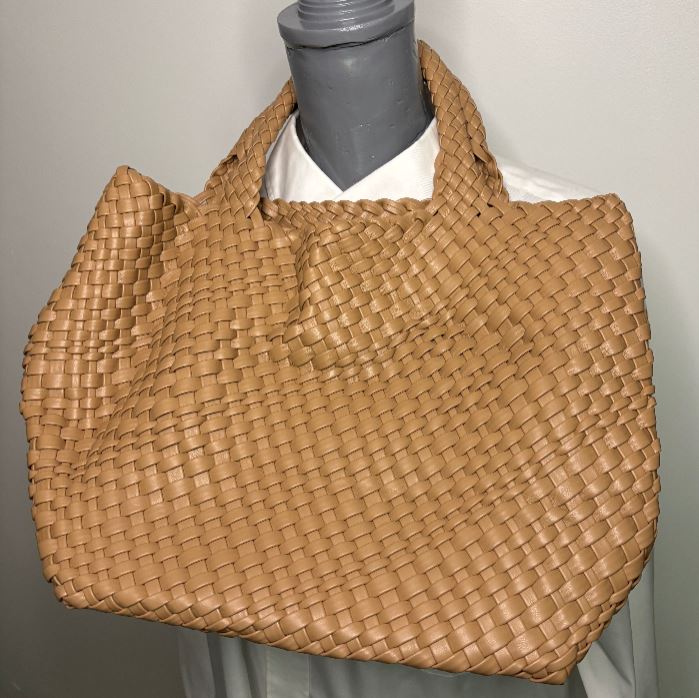 Woven brown handbag on a mannequin against a neutral background