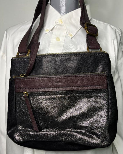 Black glittery handbag with brown straps on a white shirt background