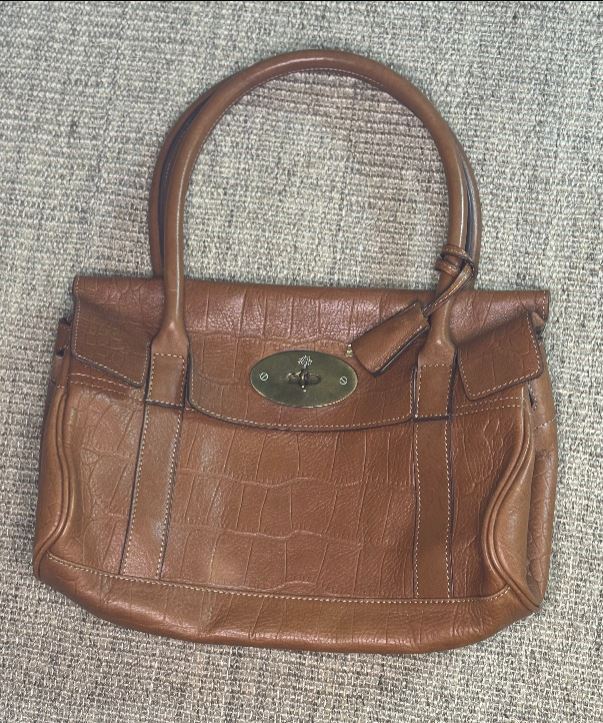 Brown leather handbag with a visible brand logo on a textured surface