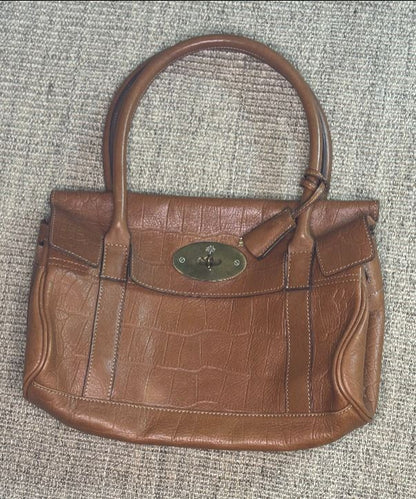 Brown leather handbag with a visible brand logo on a textured surface