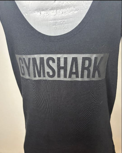 Black tank top with 'GYMSHARK' logo on a beige background