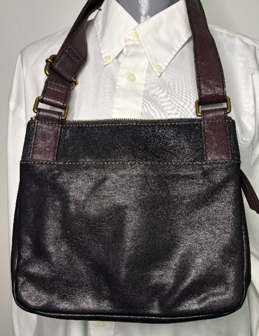 Black leather handbag with brown straps on a white shirt background