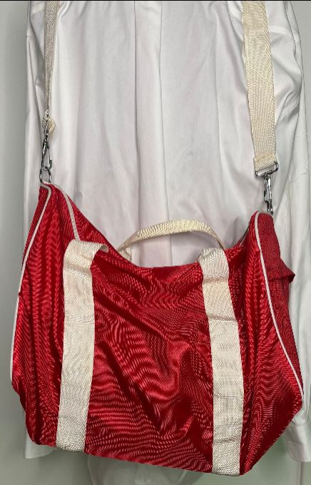 Red textured handbag with beige handle and strap on a white background