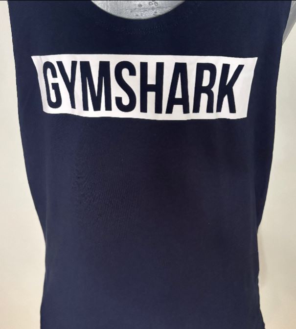 Navy blue tank top with 'GYMSHARK' logo on a beige background