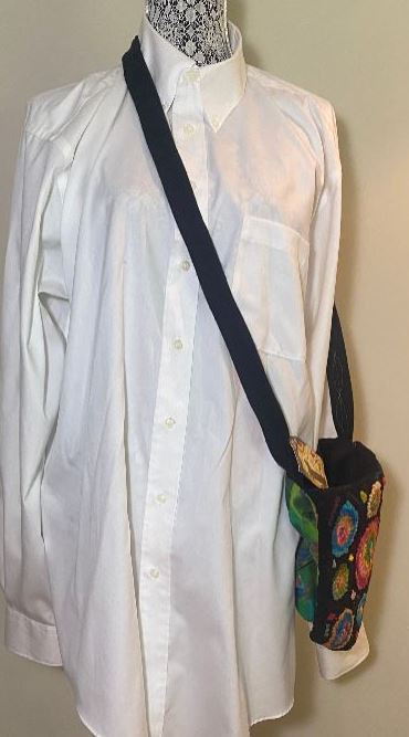 Mannequin wearing a white shirt with a colorful pouch on a strap against a neutral background
