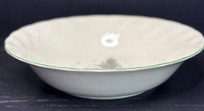 White ceramic bowl with green rim on a dark background